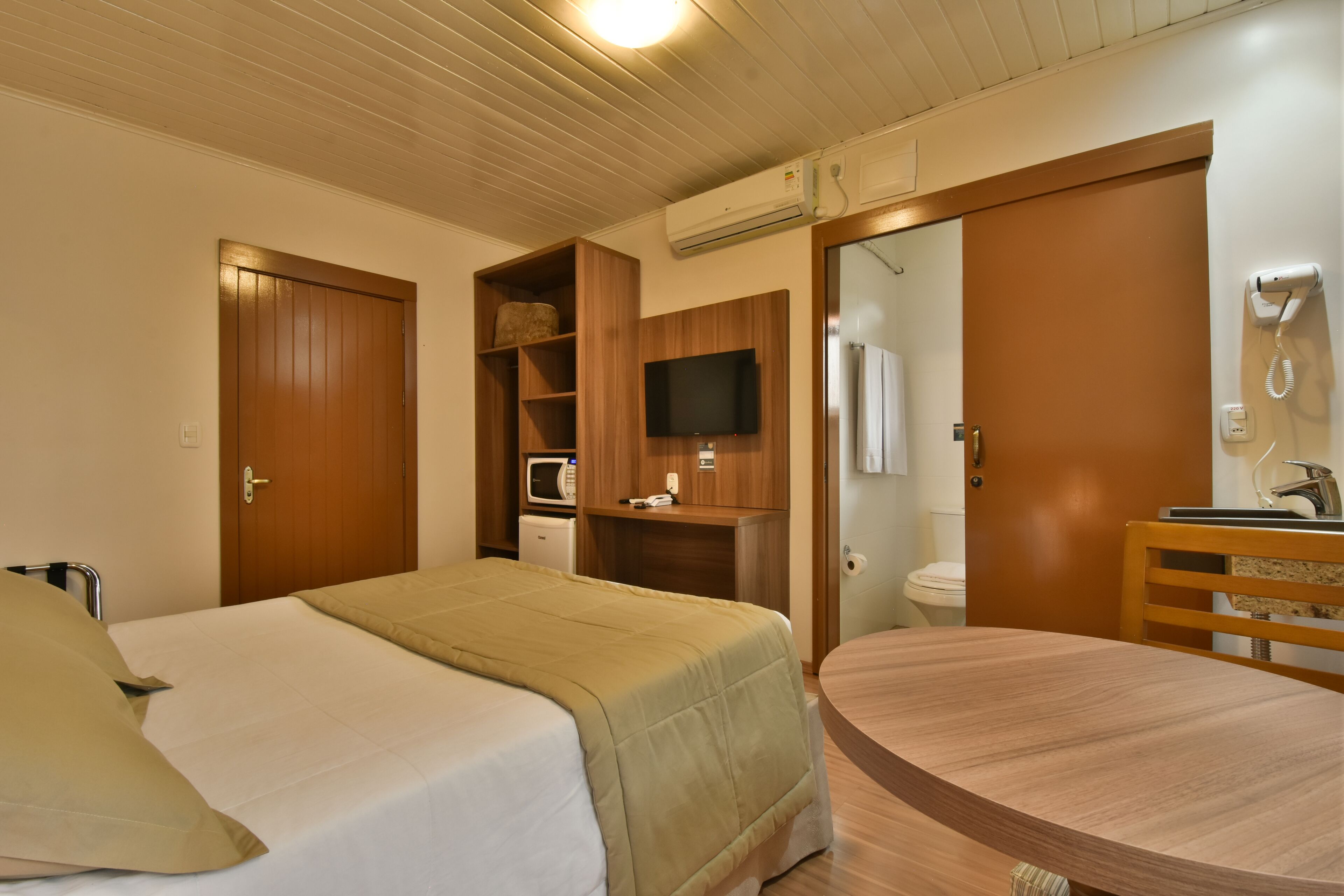 A hotel room with a bed, a desk, a television, and a bathroom.