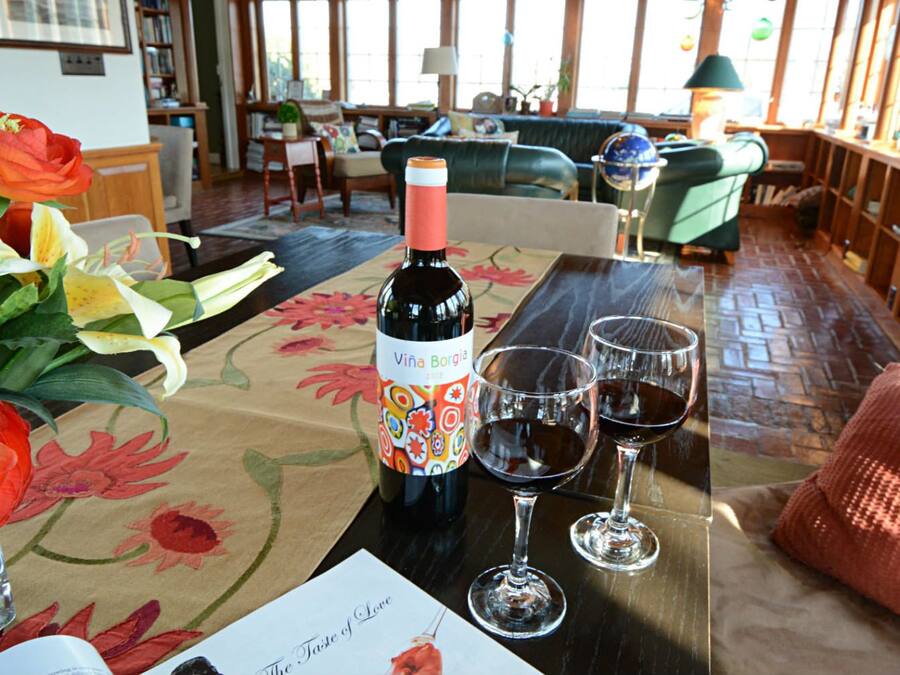 Una mesa con una botella de vino, dos copas de vino y un arreglo floral.