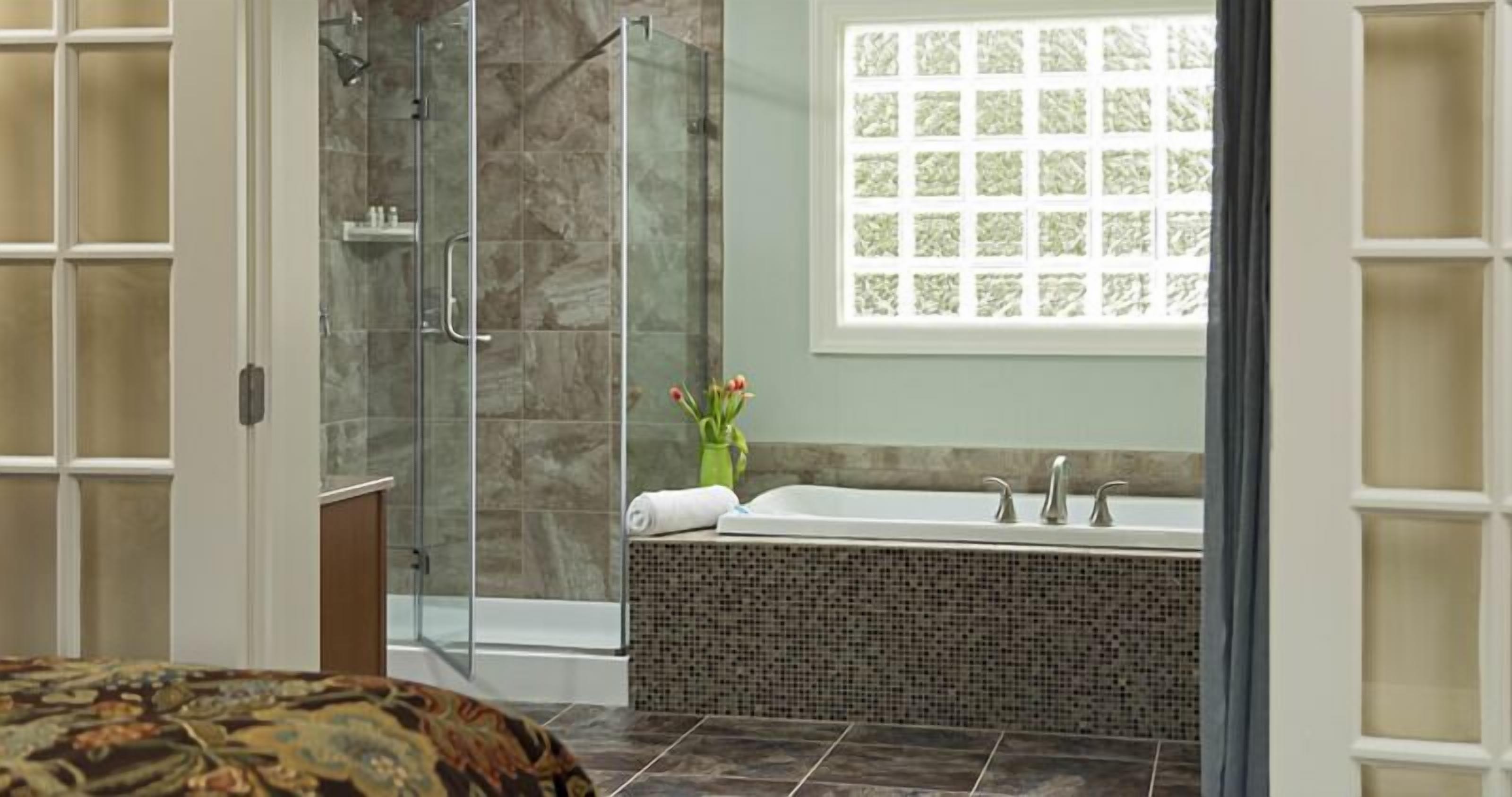 Un baño con cabina de ducha de vidrio, una bañera independiente y un ventanal con vistas decorativas.