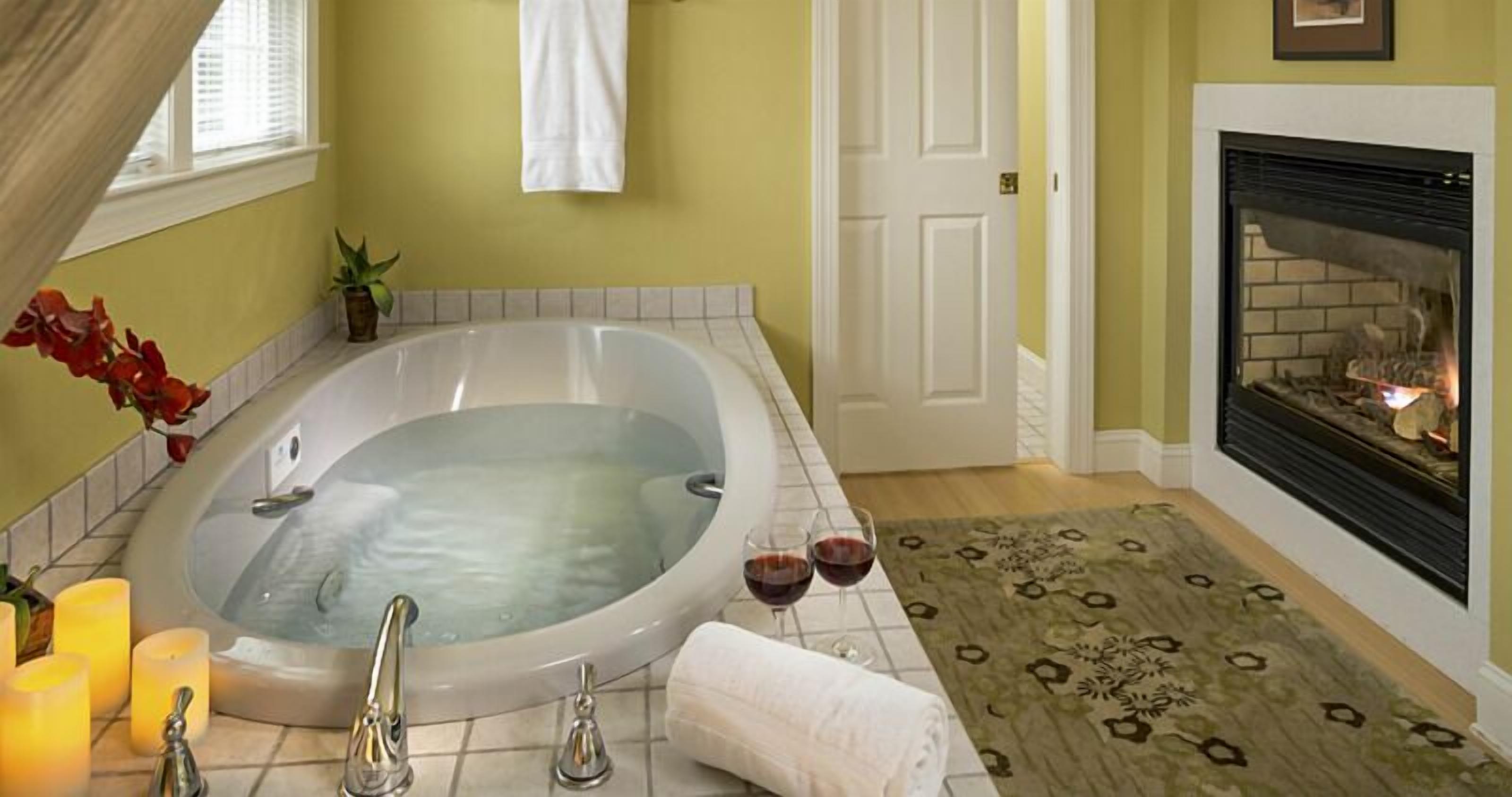 A bathroom with a large bathtub, a fireplace, and candles.