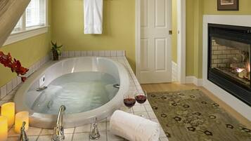 A bathroom with a large bathtub, a fireplace, and candles.