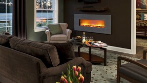 A modern living room with a large sofa, a small armchair, a coffee table, and a fireplace.