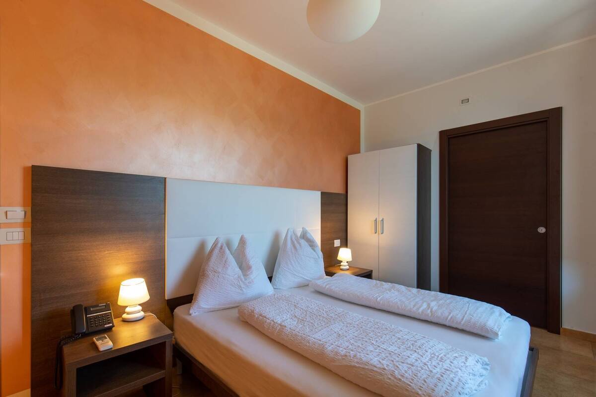 Ein Hotelzimmer mit Bett, Nachttischlampen, Telefon und Kleiderschrank.