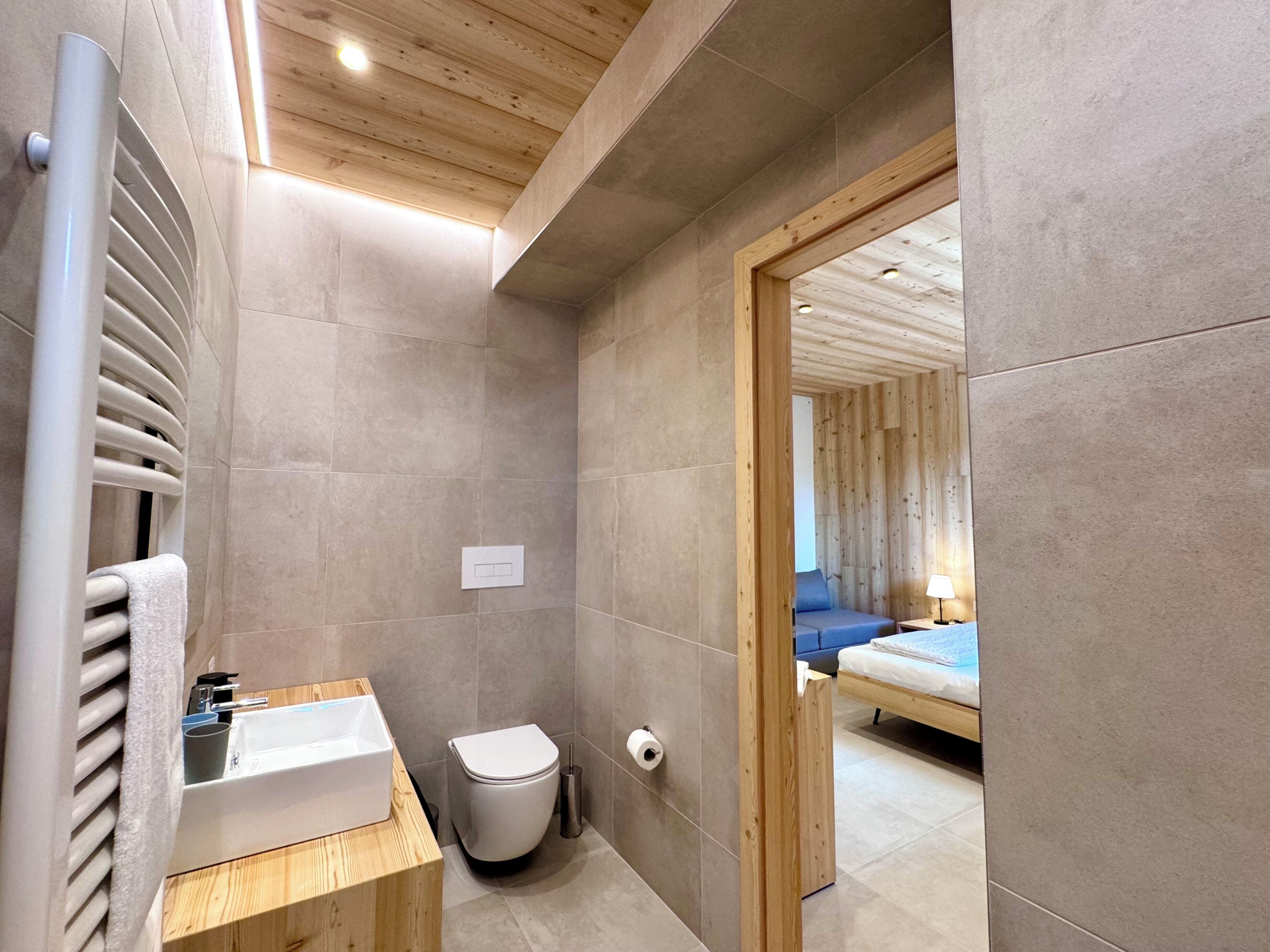 A modern bathroom with a wooden vanity, a toilet, and a shower area.
