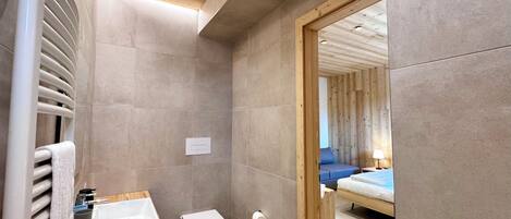 A modern bathroom with a wooden vanity, a toilet, and a shower area.