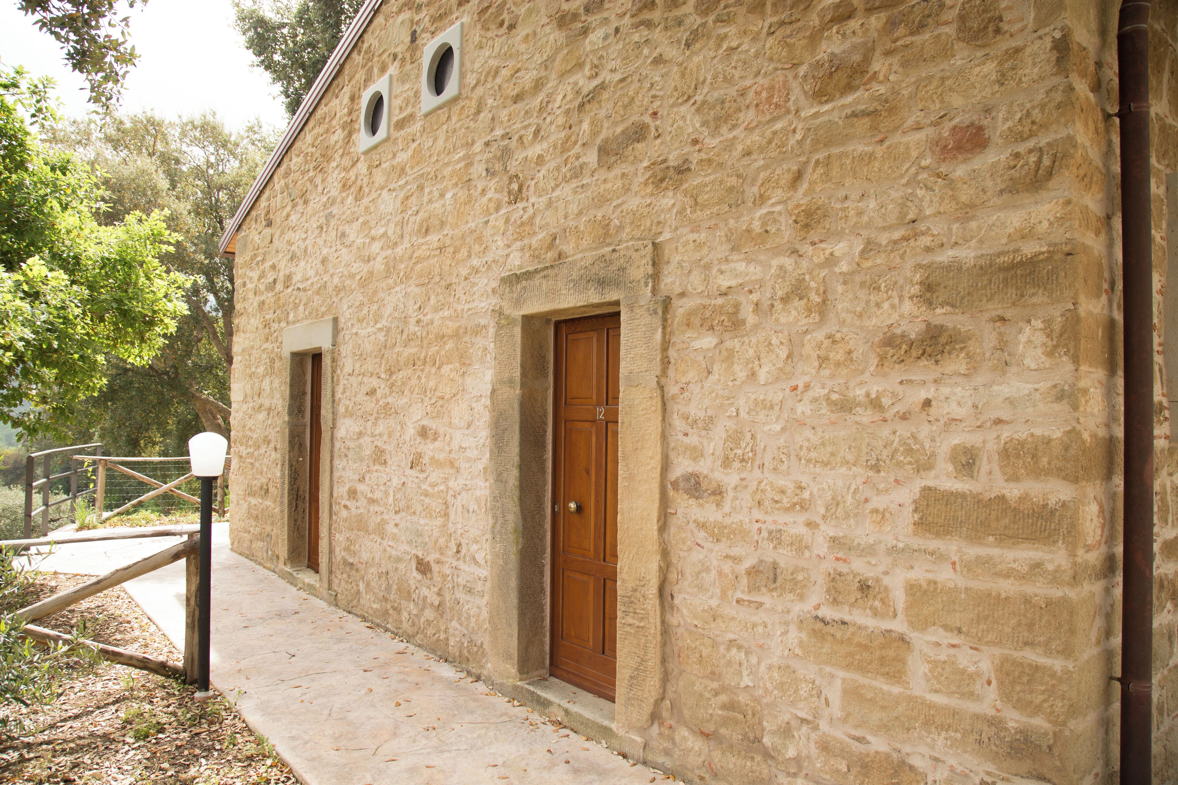 Un edificio de piedra con dos puertas de madera y un pequeño ventanal.