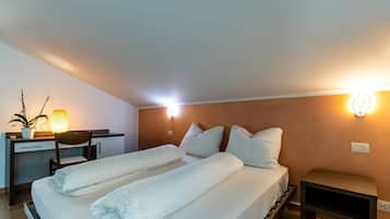 Ett hotellrum med en säng, sängbord, ett skrivbord, en stol och en väggmonterad lampa.