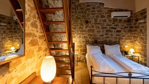A bedroom with a stone wall, a wooden ladder, a bed with white linens, and a wall-mounted air conditioner. - Villa Ginevra Resort Agrituristico (Ficarra)