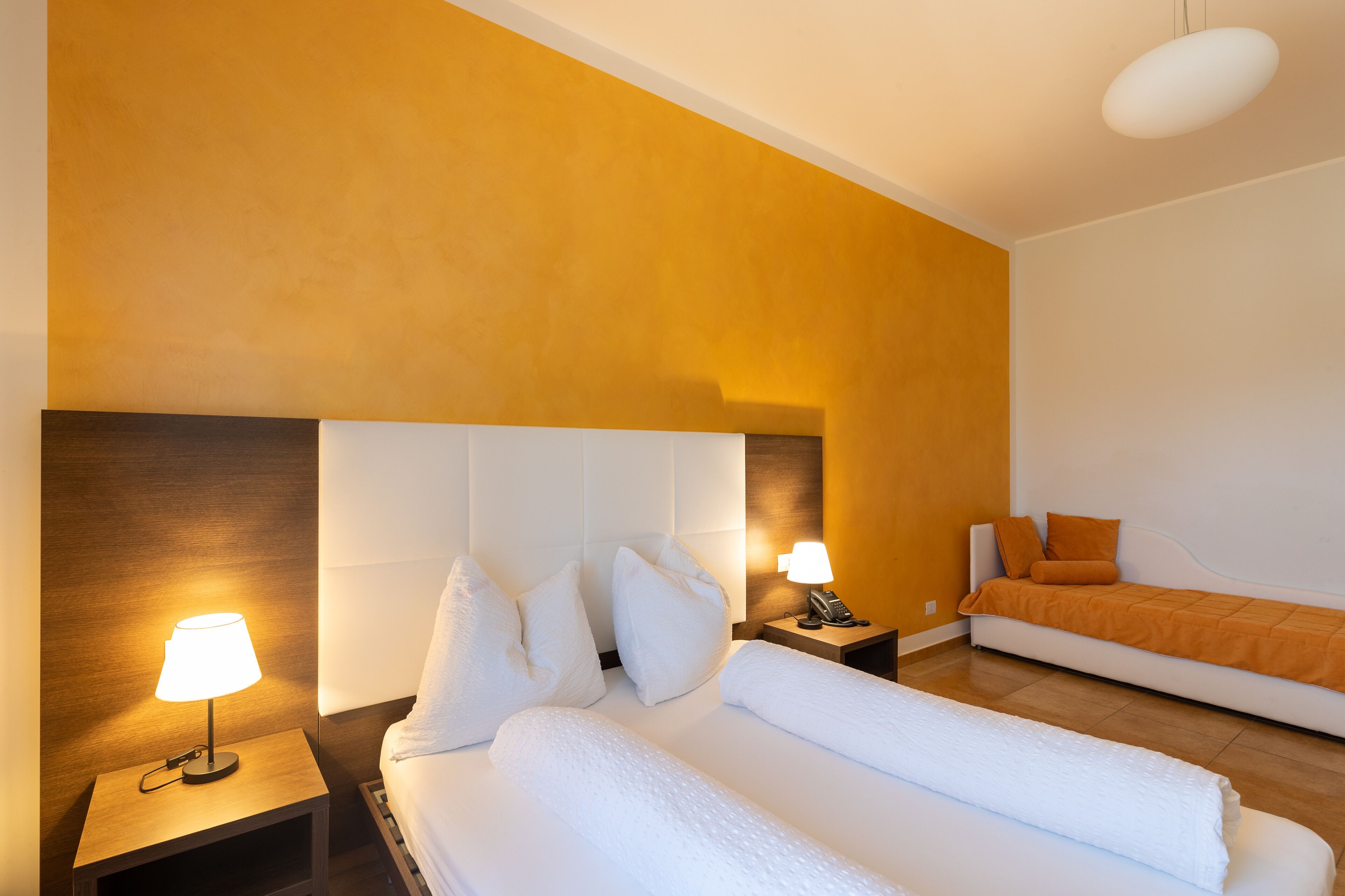 Une chambre d’hôtel avec un grand lit, un petit canapé, une table de chevet avec une lampe et un téléphone.