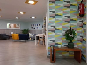 Ein modernes Interieur mit einer Wand im geometrischen Muster, einem Holztisch mit einer Vase und einem Feuerlöscher.