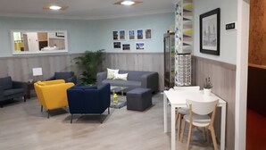Una sala de estar moderna con un sofá gris, un sillón amarillo y una mesa de comedor blanca.