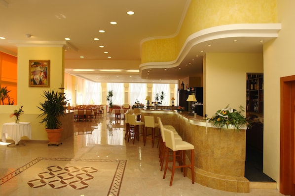 Un hall de hotel con una zona de bar, asientos y una recepción.