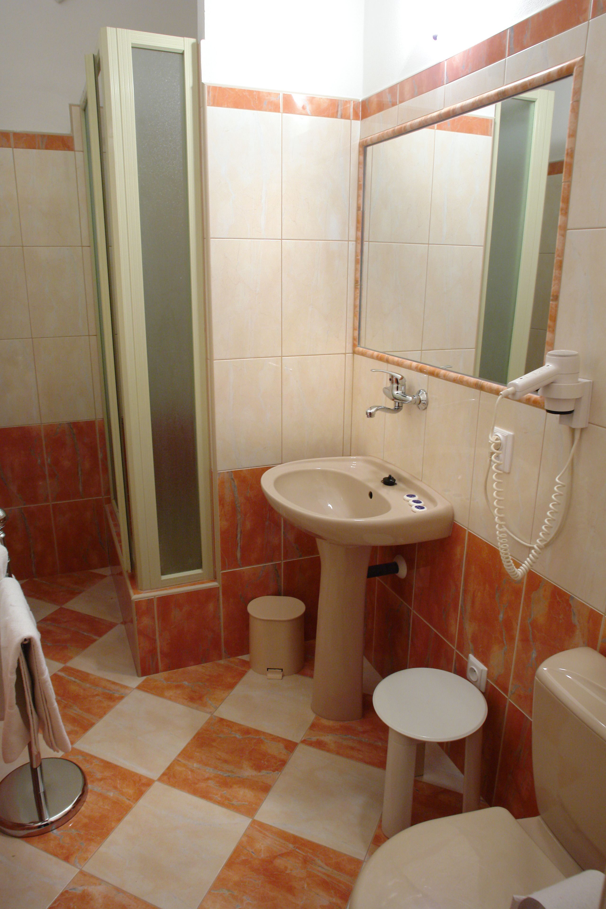 A bathroom with a sink, mirror, toilet, and a small round table.
