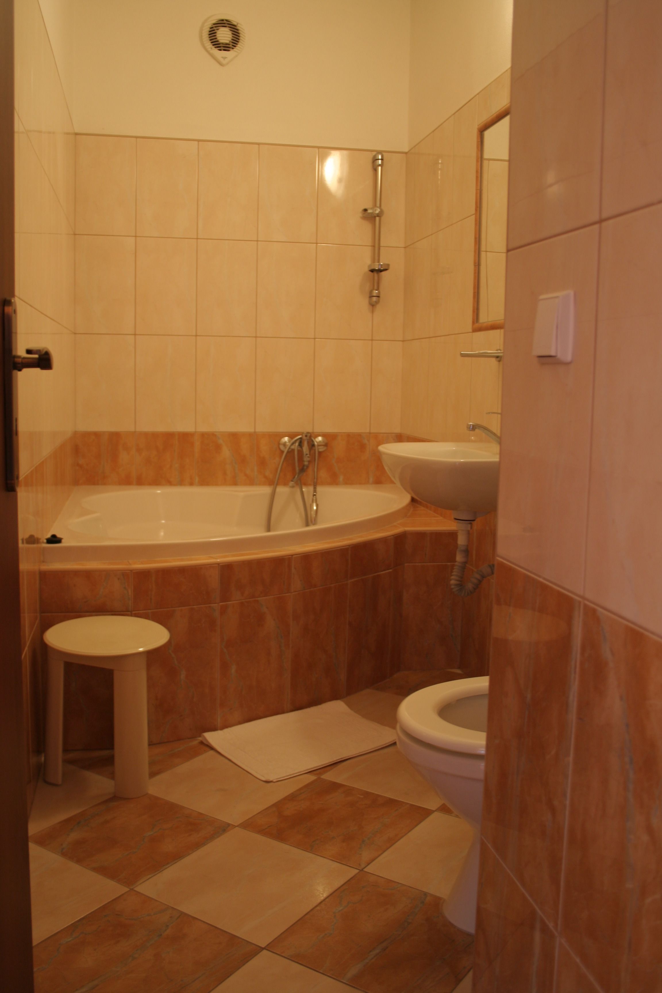 Un baño con bañera, lavamanos, inodoro y un taburete pequeño.