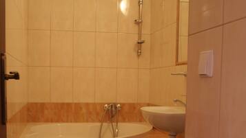 Un baño con bañera, lavamanos, inodoro y un taburete pequeño.