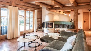 A cozy log cabin interior with a fireplace, a sofa, and a dining table. - Chalets&Apartments beim Waicher (Ruhpolding)