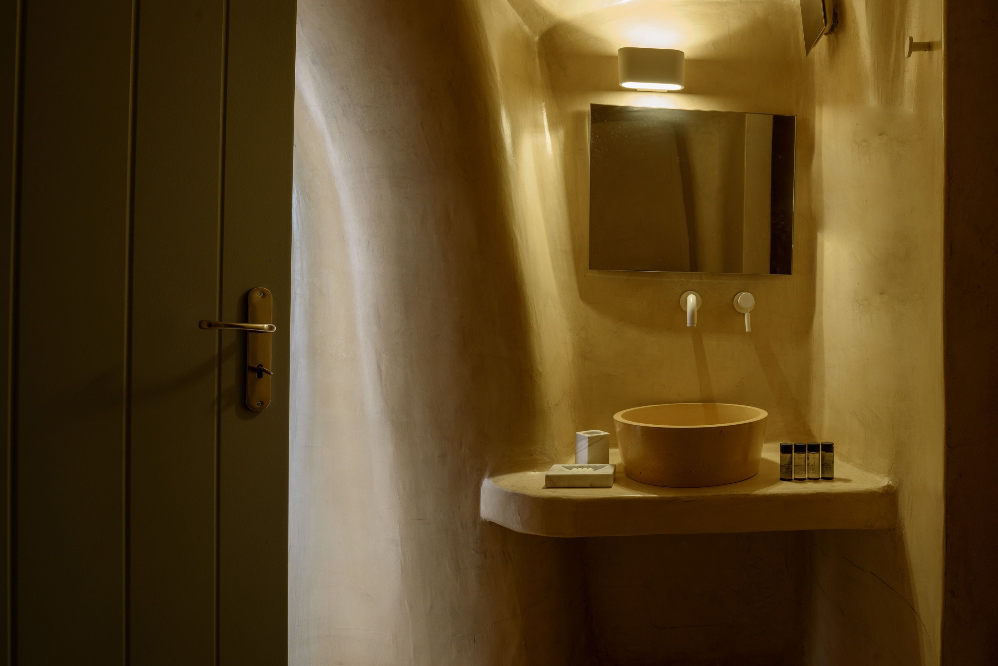 A bathroom with a sink, mirror, and a towel dispenser.