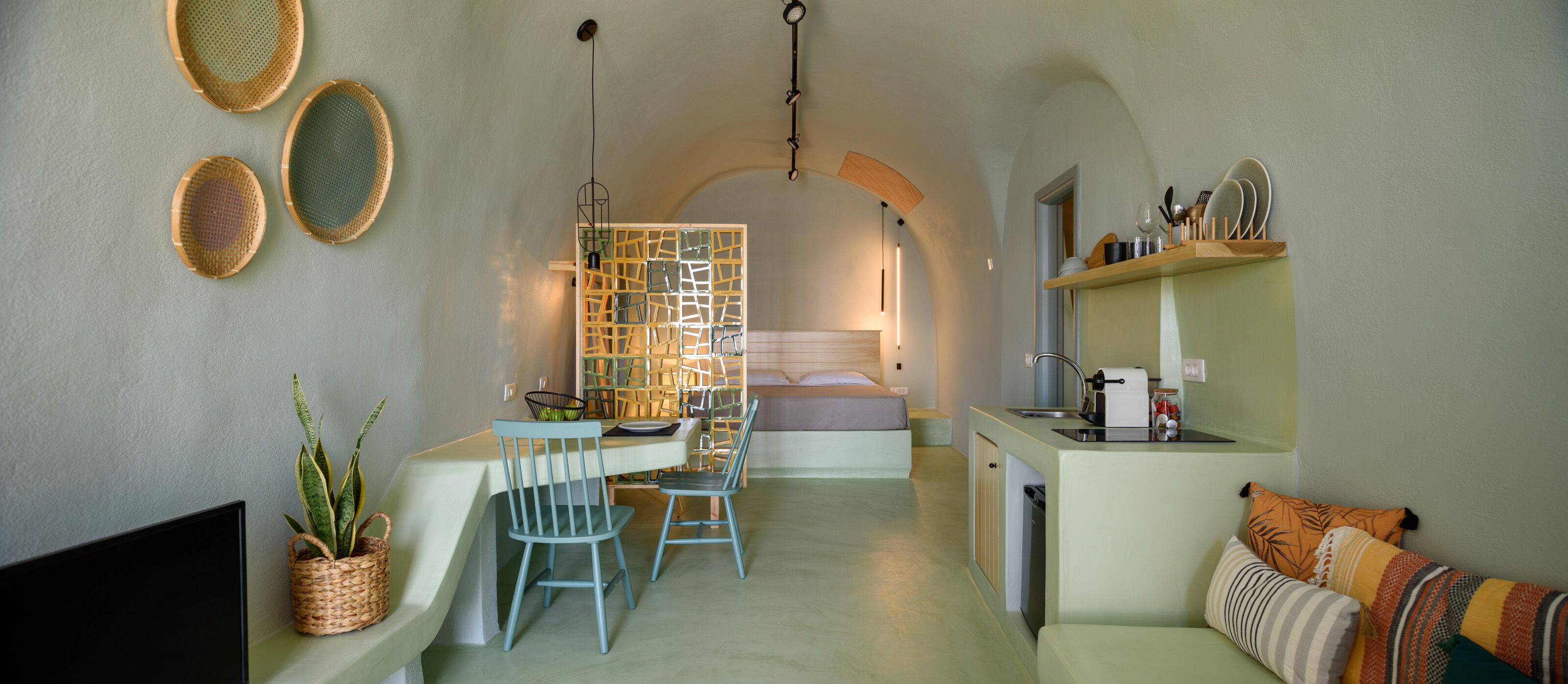 A compact living space with a kitchenette, a dining area, and a bed.