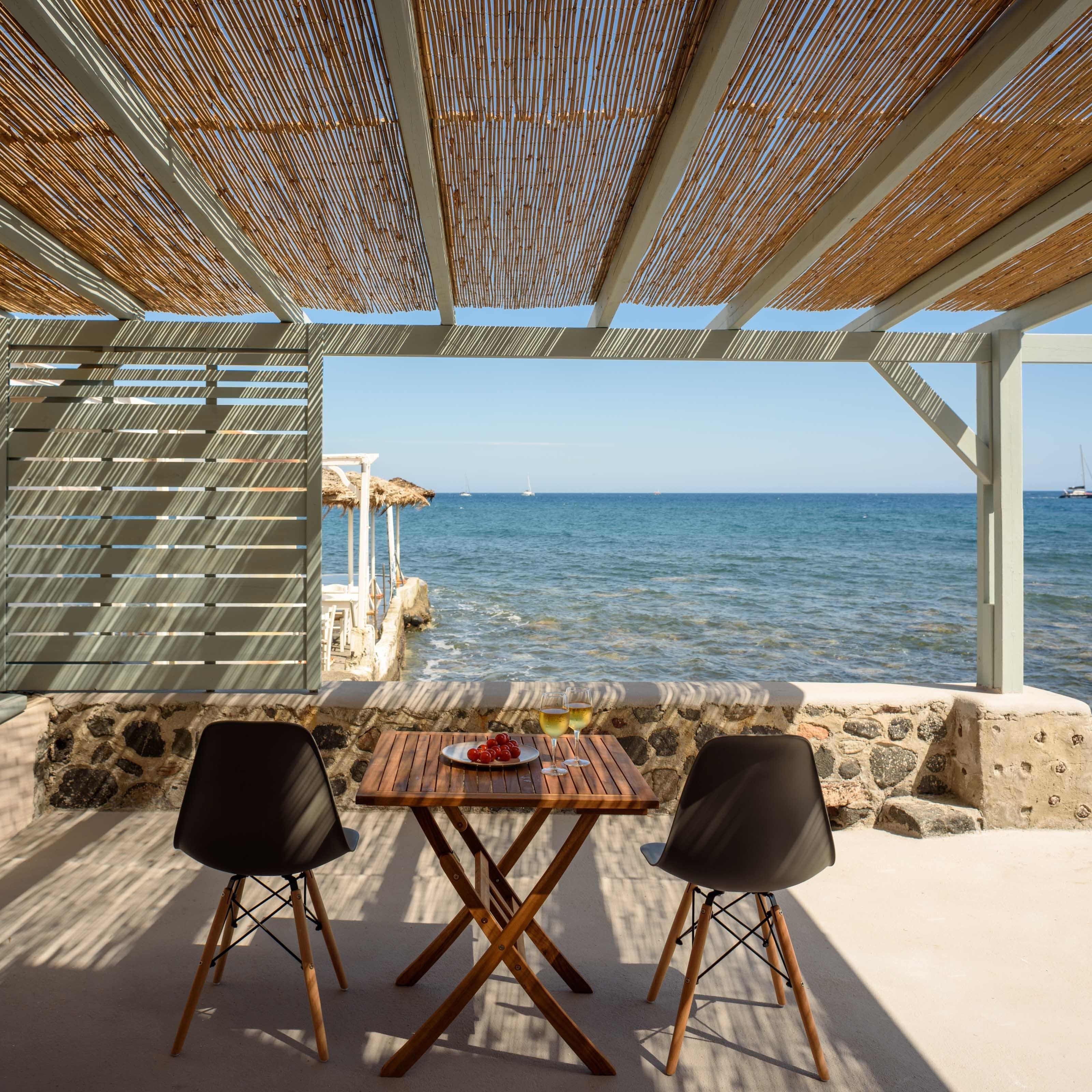 Un espace extérieur aménagé avec une table et deux chaises, offrant une vue sur la mer.