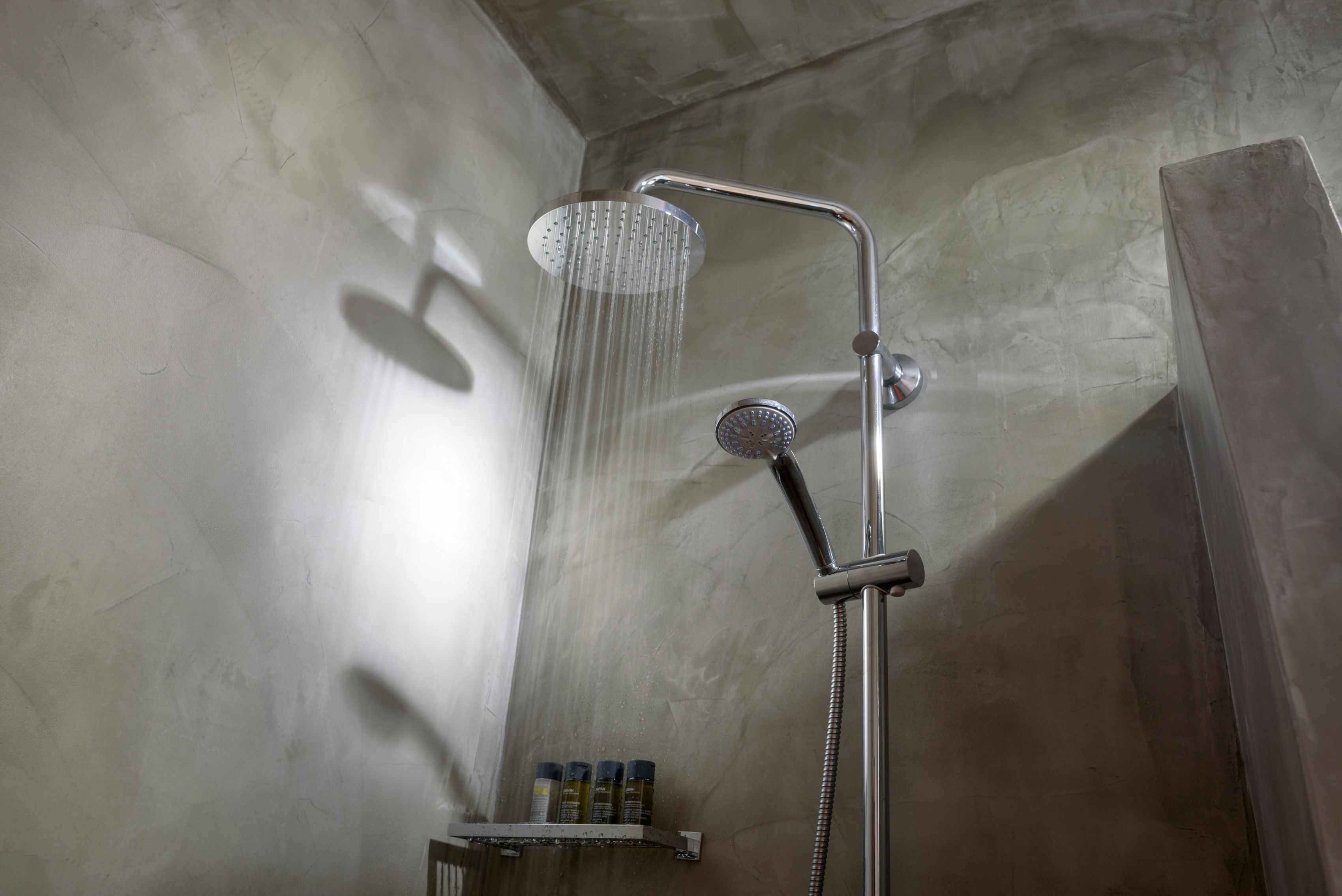Une douche équipée d’un pommeau de douche à main et de commandes murales.
