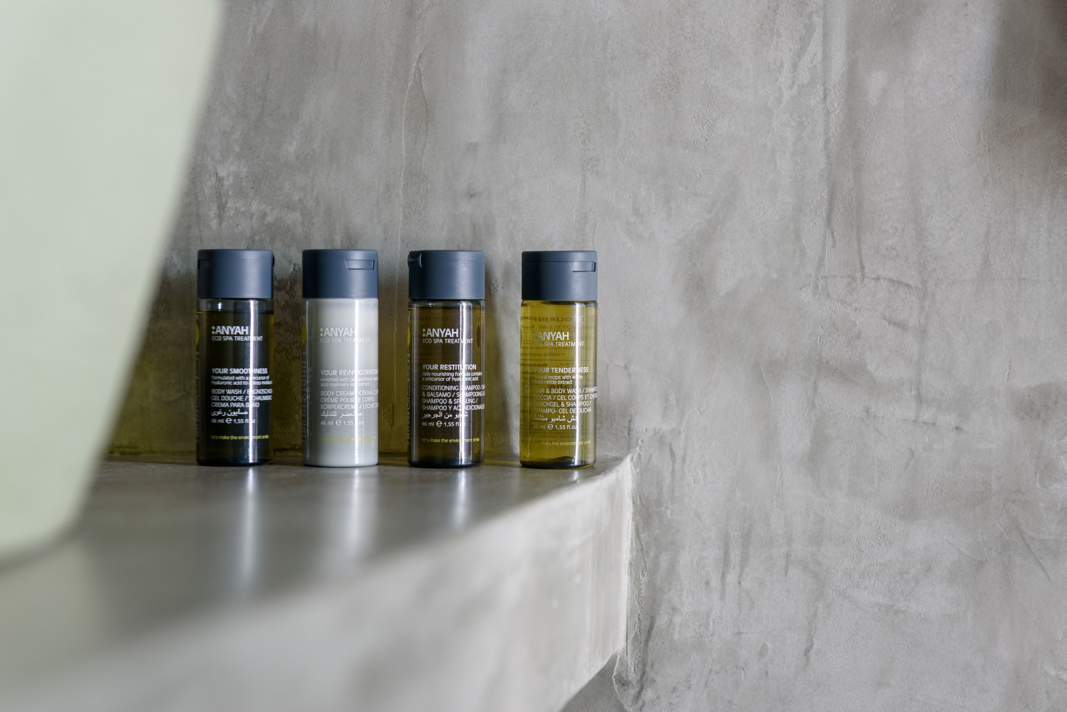 Four bottles of Anyah eco spa treatment on a shelf against a textured wall.