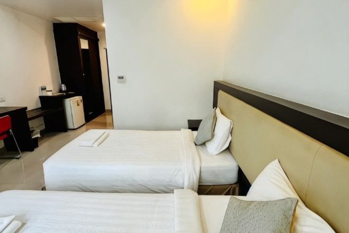 Habitación de hotel con dos camas, un escritorio y una pequeña cocina.