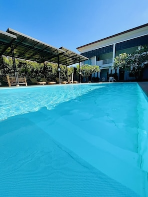 A swimming pool with a covered area and lounge chairs. - Bualinn Resort Nongkhai (Nong Khai)