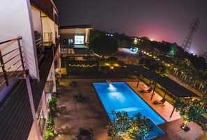 Una piscina al aire libre, sombrillas, sillones reclinables de piscina