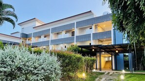 A modern multi-story hotel with a covered outdoor area and a well-maintained garden. - Bualinn Resort Nongkhai (Nong Khai)