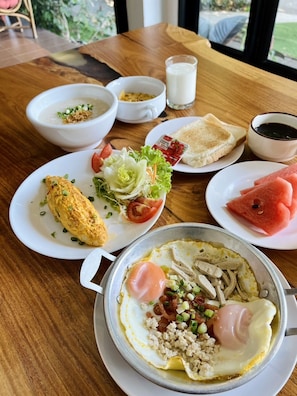 A breakfast setting with various dishes including an omelette, toast, watermelon, and a bowl of soup. - Bualinn Resort Nongkhai (Nong Khai)