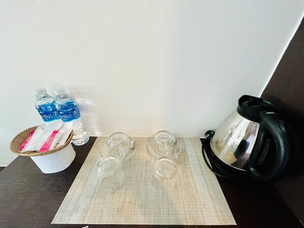 Una mesa con dos botellas de agua, un cesto de pañuelos y una tetera.