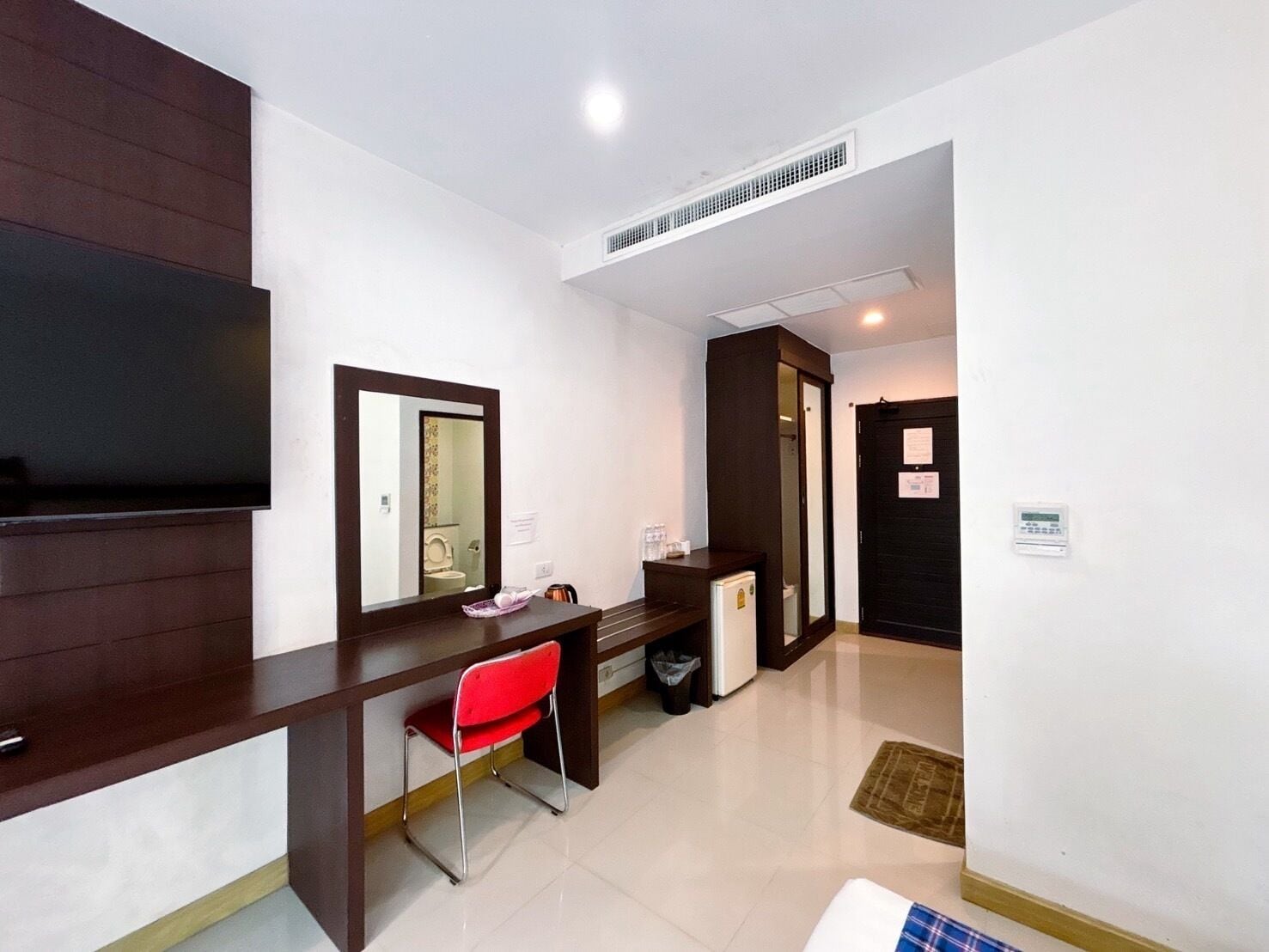 A hotel room with a desk, chair, television, and a door leading to another room.