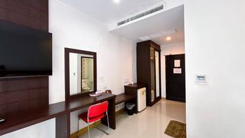 A hotel room with a desk, chair, television, and a door leading to another room.