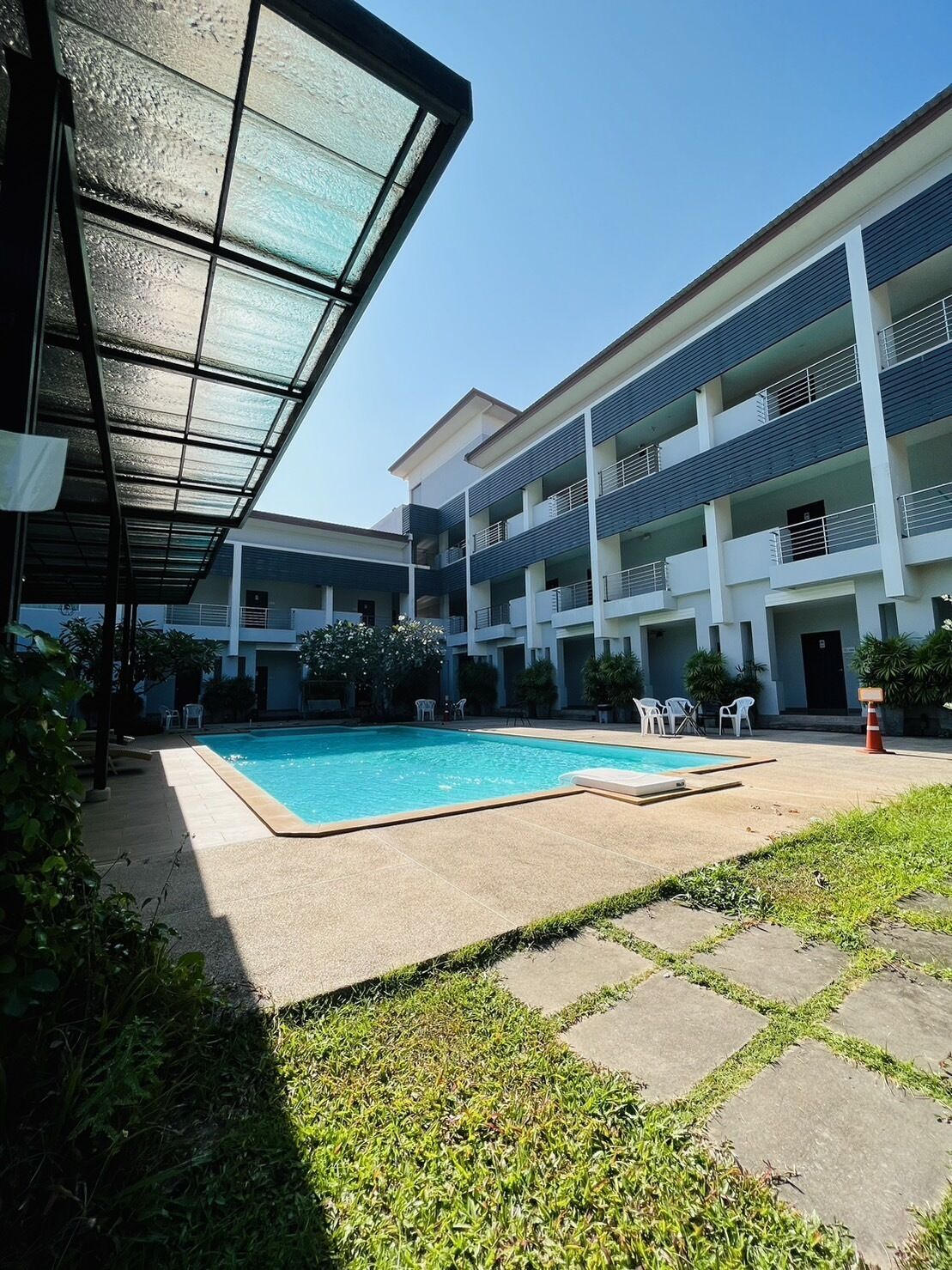 Ein modernes Gebäude mit Pool, Sitzgelegenheiten im Freien und einer überdachten Terrasse.