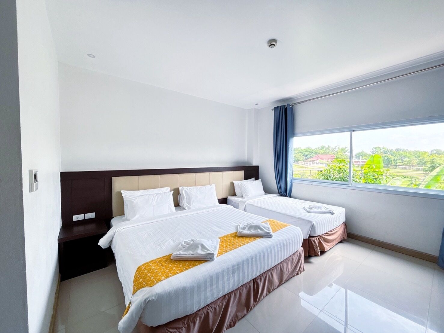 Une chambre d’hôtel avec deux lits, une grande fenêtre et une vue sur l’extérieur.