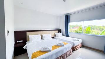 A hotel room with two beds, a large window, and a view of the outdoors.