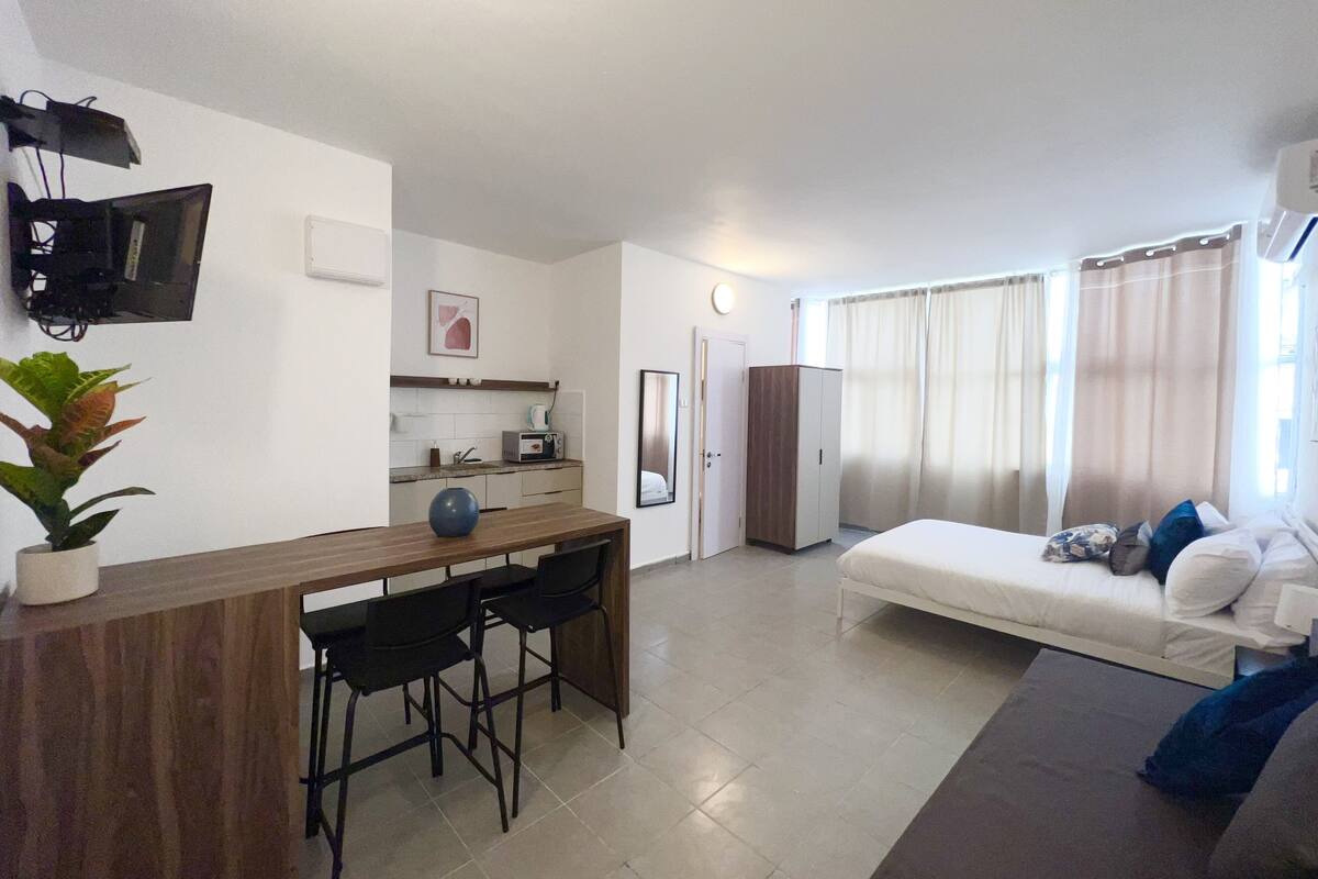 A compact living space with a kitchenette, a dining area, and a bed.