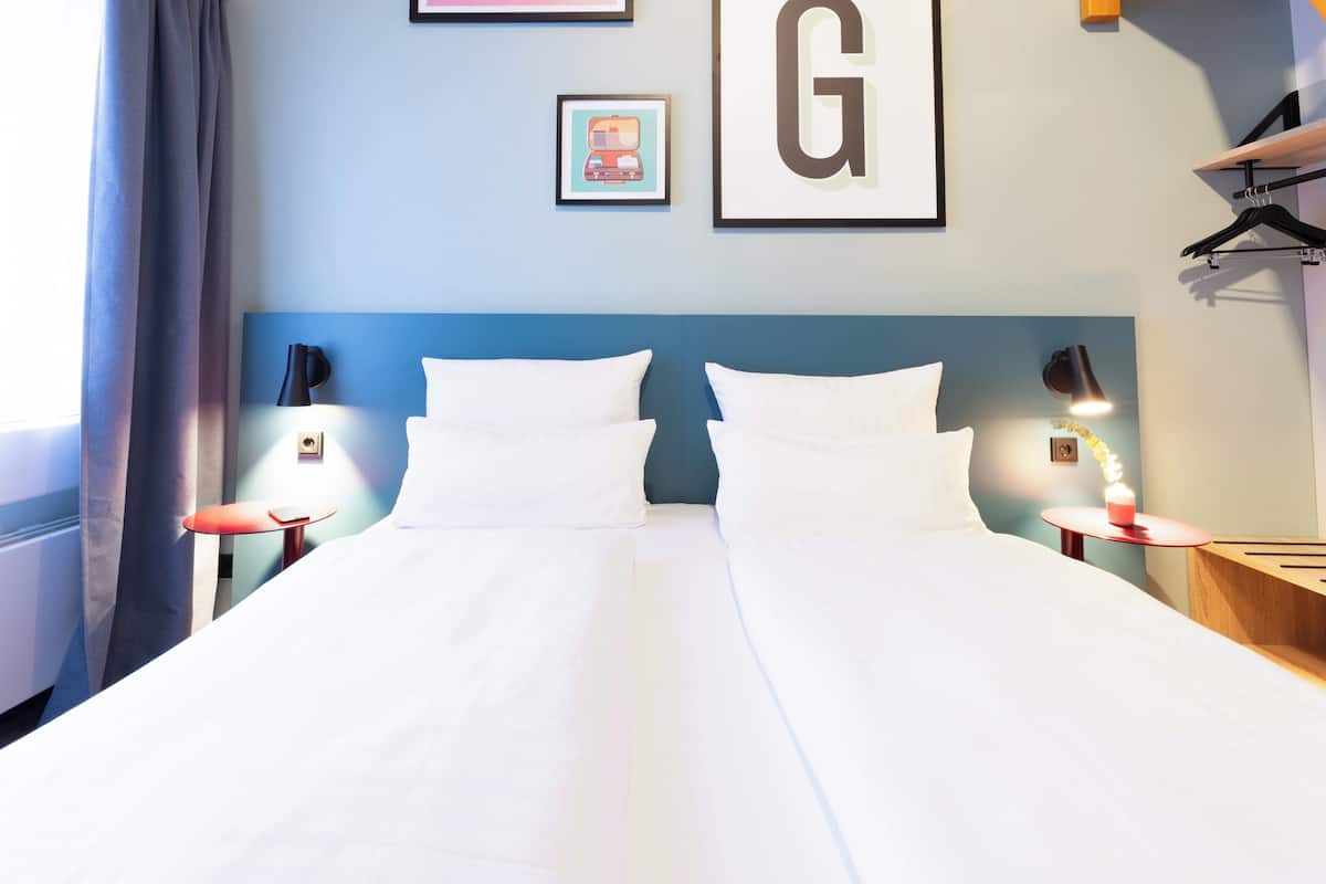 Hotelkamer met een groot bed, twee nachtkastjes, een wandlamp en een lijst met een afbeelding.