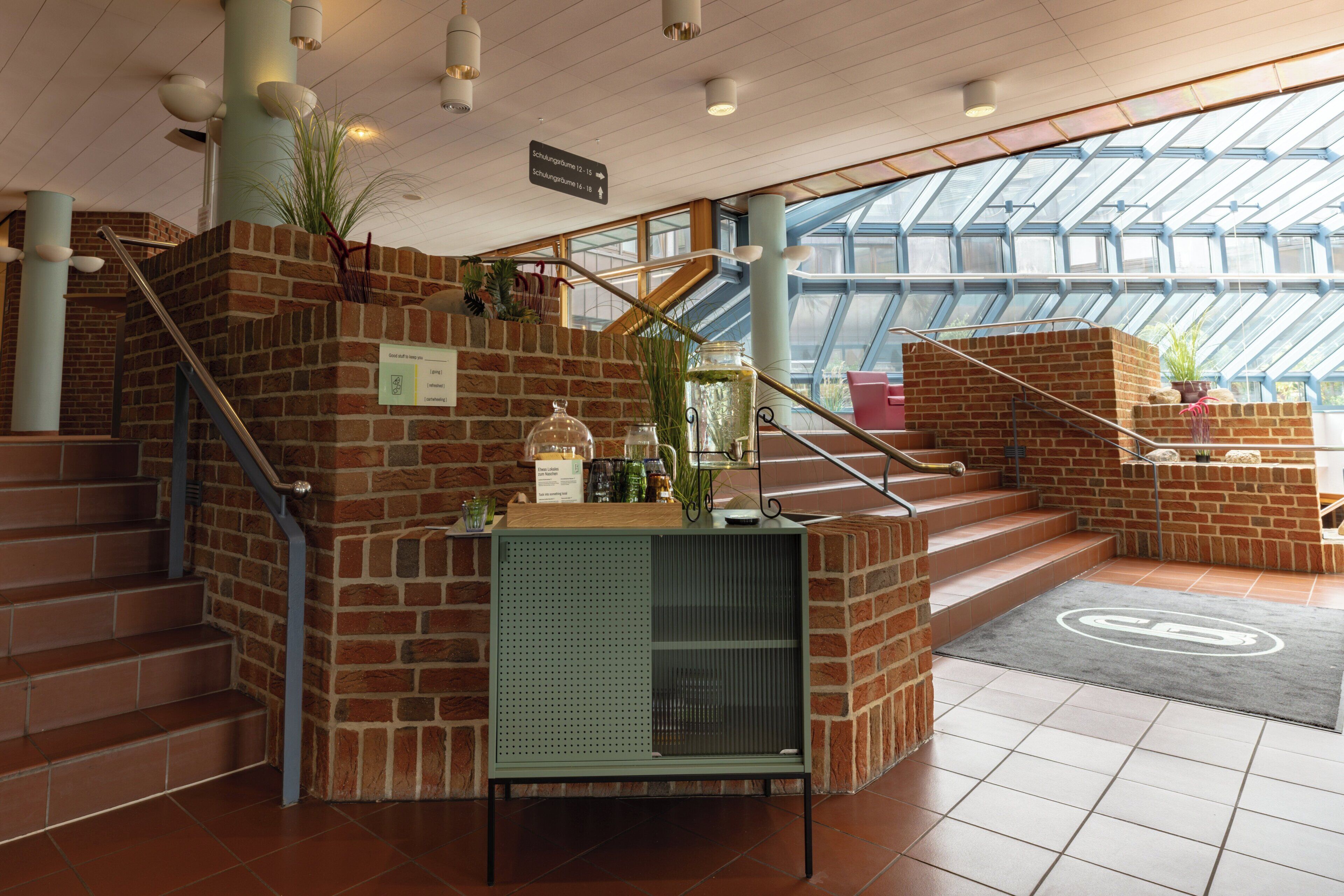 A staircase with a metal railing, a green metal console table with a plant, and a glass door leading to a balcony.
