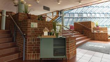 A staircase with a metal railing, a green metal console table with a plant, and a glass door leading to a balcony.