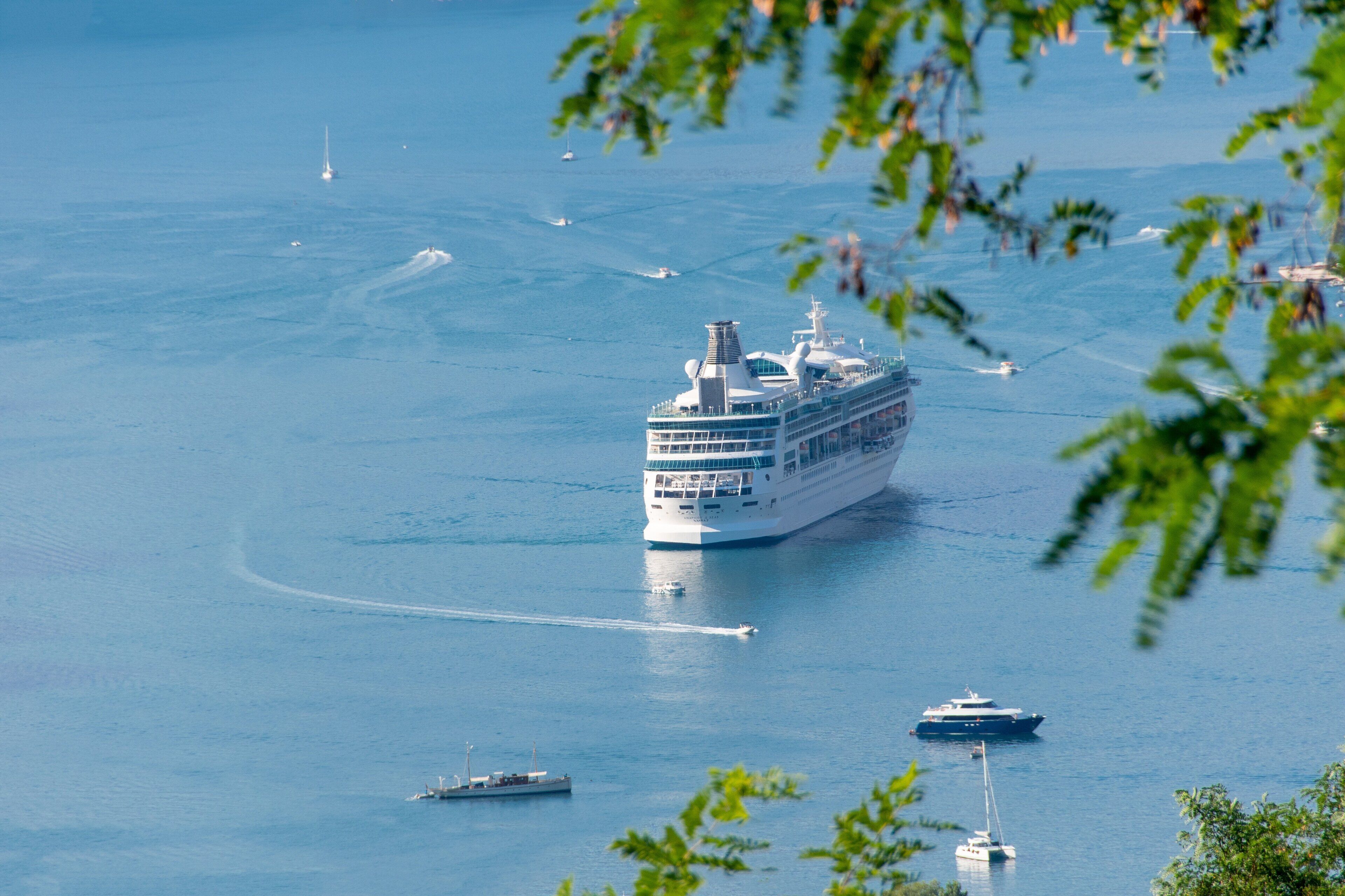 Ein großes Kreuzfahrtschiff auf dem Wasser, umgeben von kleineren Booten.