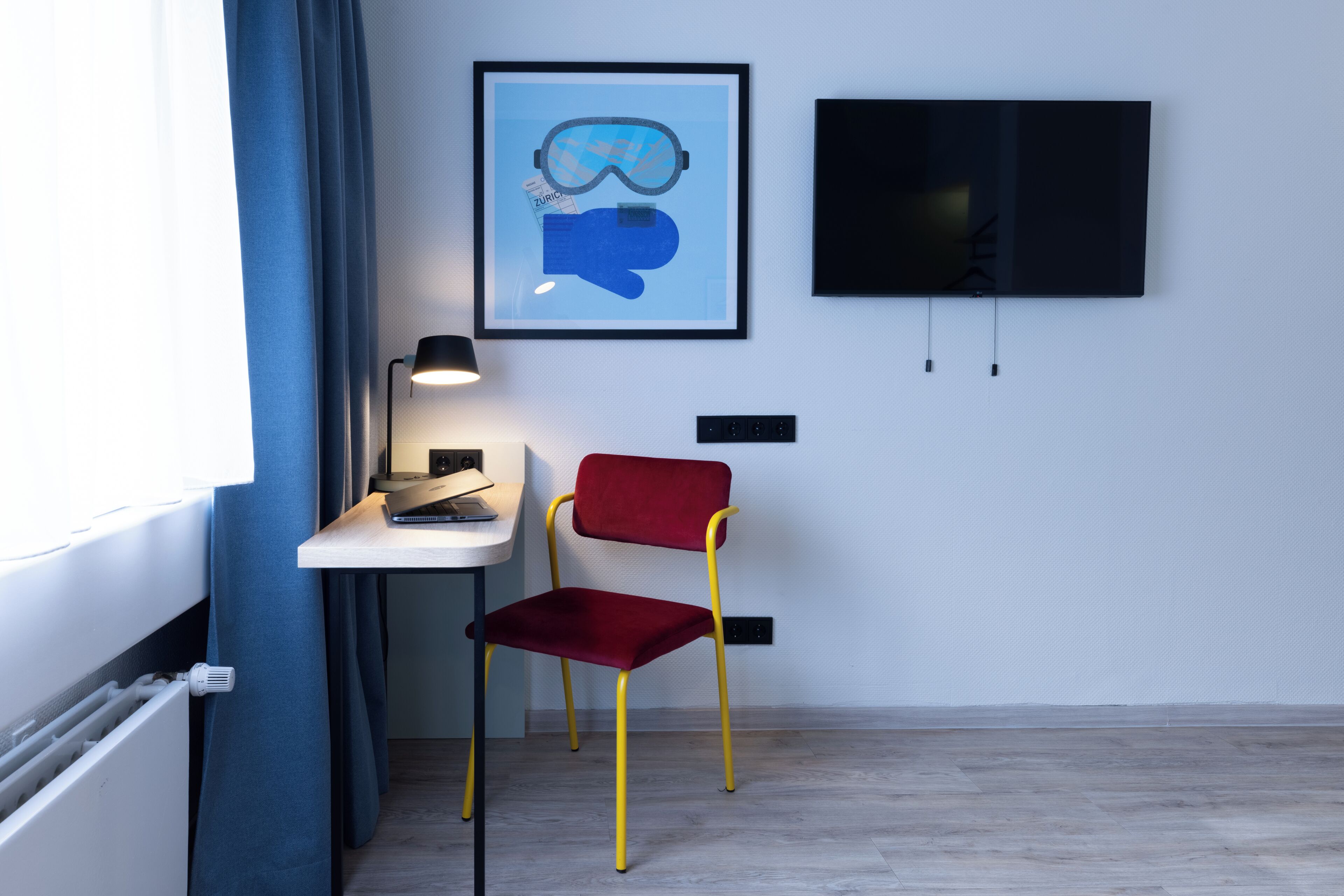 Una habitación con escritorio, silla, una obra de arte enmarco y televisor.