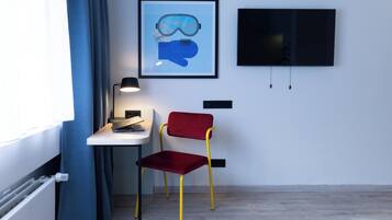 Una habitación con escritorio, silla, una obra de arte enmarco y televisor.