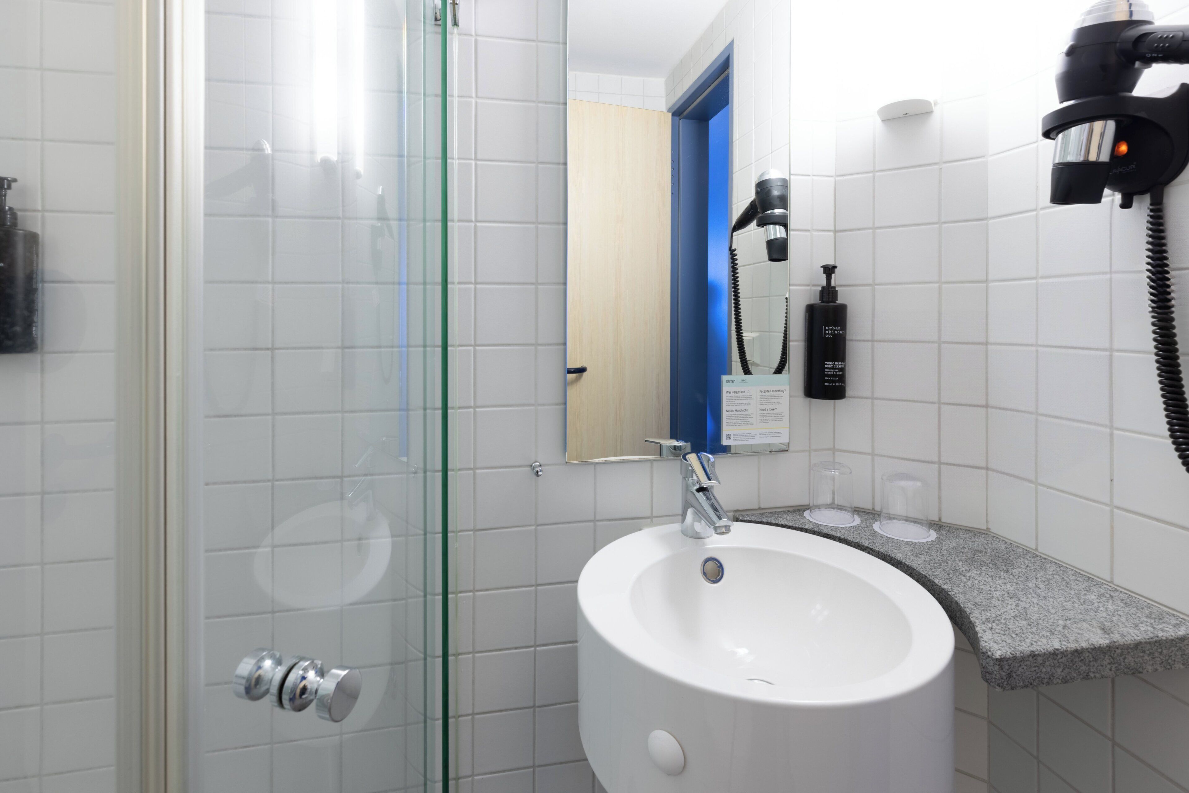A bathroom with a glass shower enclosure, a white sink, and a mirror.