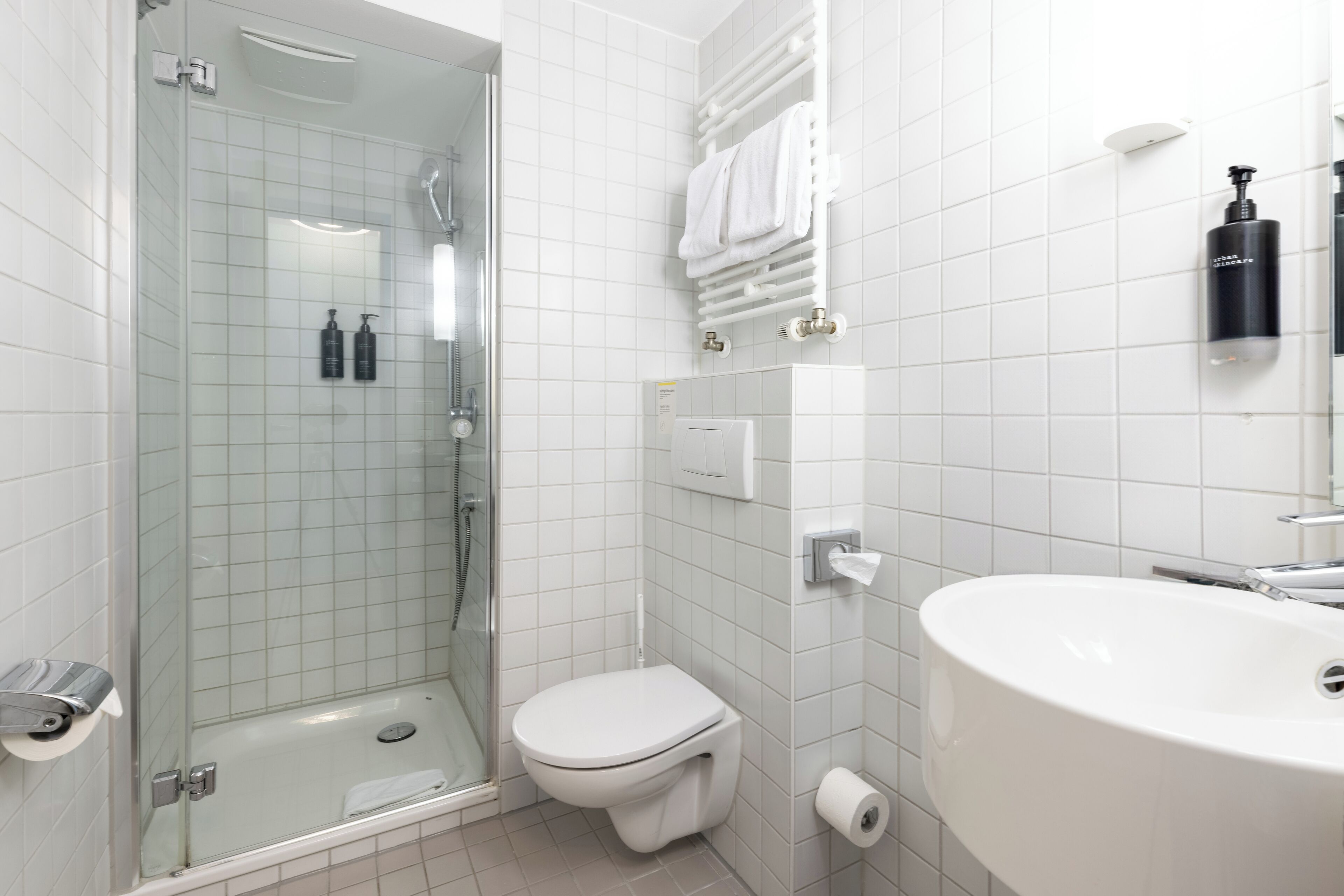 Een moderne badkamer met een douchecabine van glas, een wit toilet en een grote wastafel.