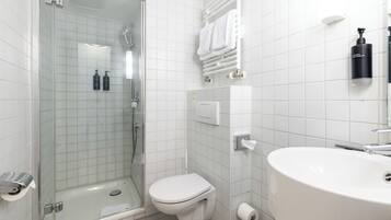 Een moderne badkamer met een douchecabine van glas, een wit toilet en een grote wastafel.