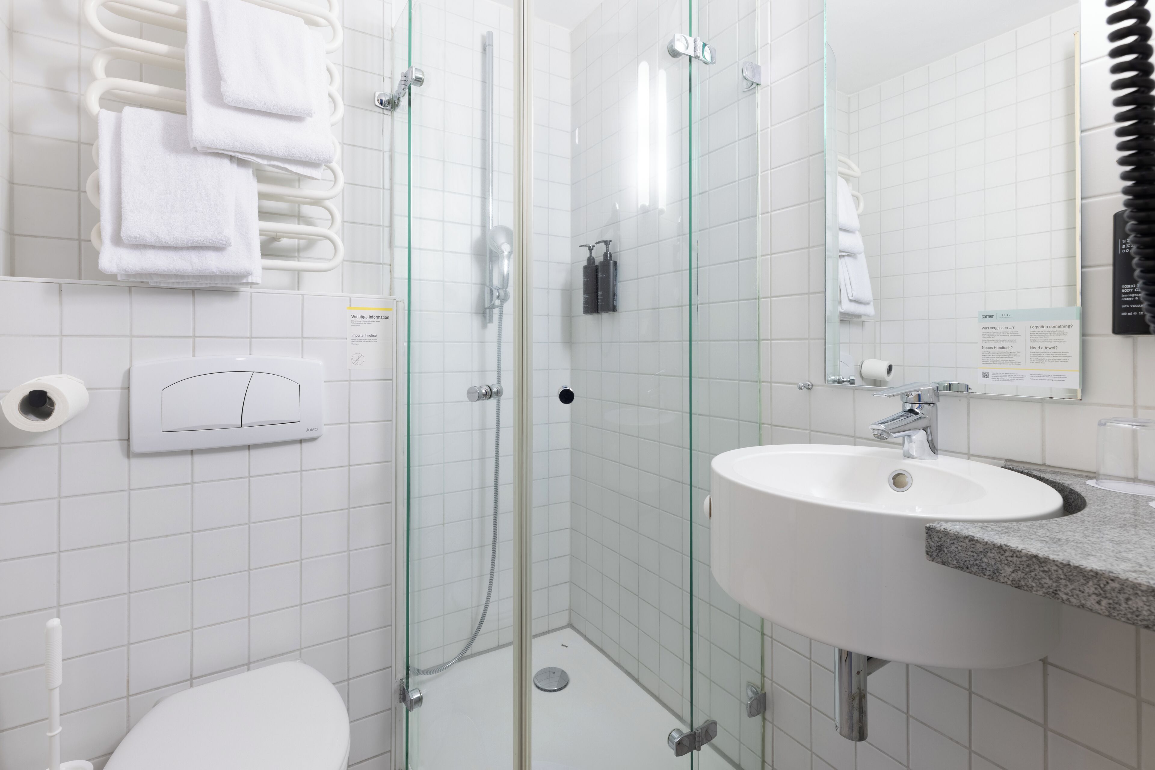 A modern bathroom with a glass-enclosed shower, a white sink, and a toilet.