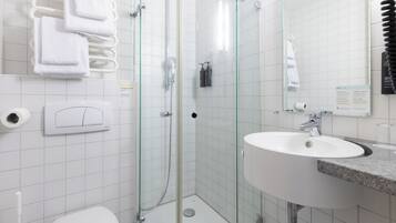 A modern bathroom with a glass-enclosed shower, a white sink, and a toilet.