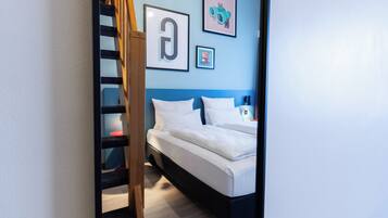 Ein Schlafzimmer mit einem Bett, einer Holzleiter und einer blauen Wand mit gerahmten Bildern.