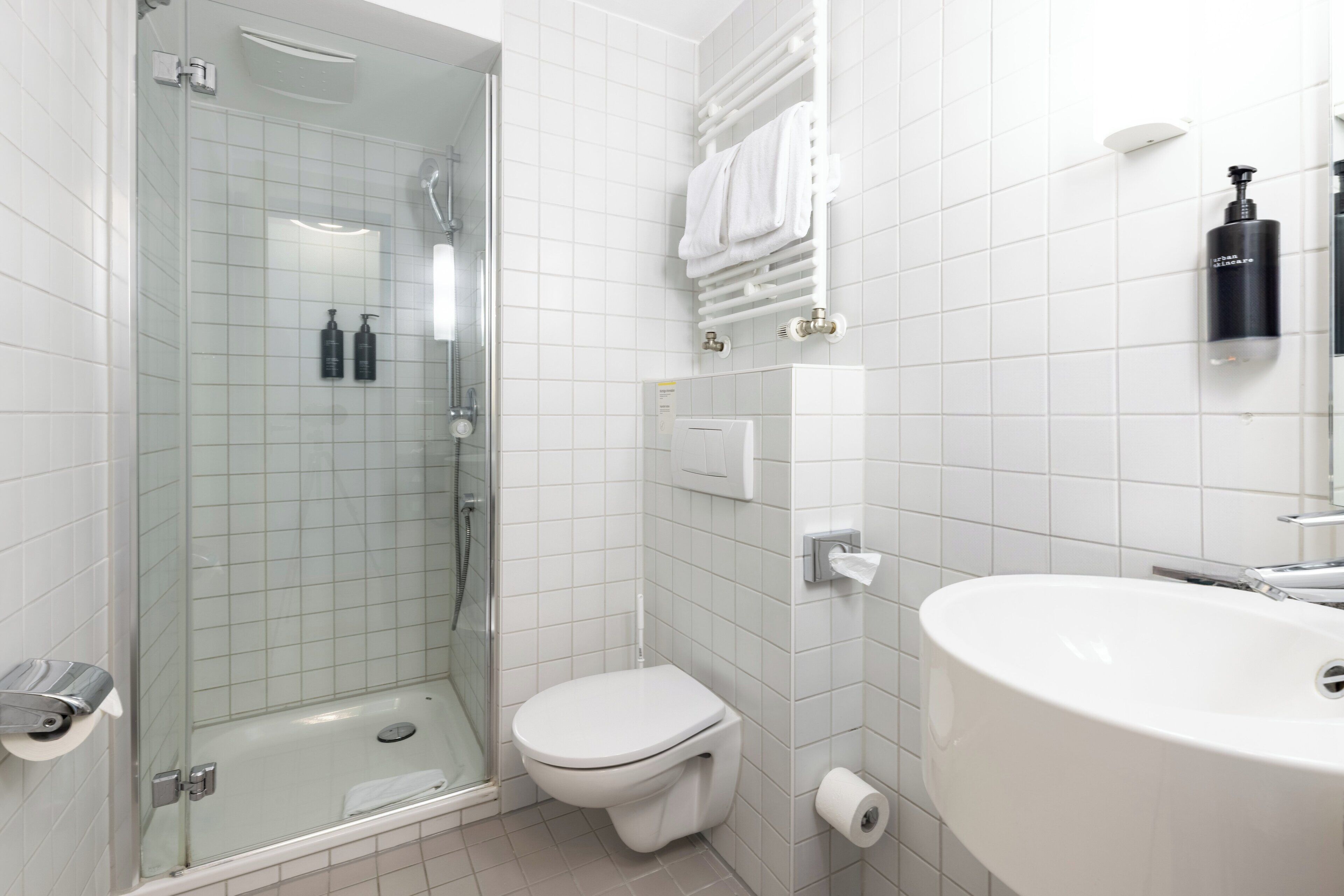 A modern bathroom with a glass-enclosed shower, a toilet, a sink, and a towel rack.
